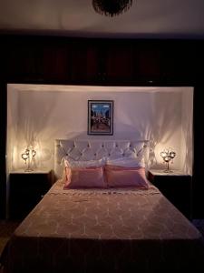 TazarkaDar louzir à Tazarka的一间卧室配有一张带两盏灯的大型白色床。