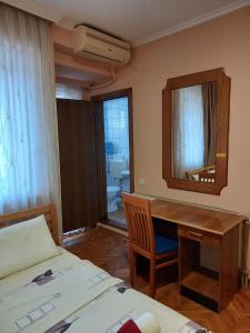 佩奇Hotel Peja的一间卧室配有书桌、一张床和镜子