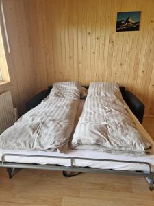 博尔加内斯Mófellsstaðakot的木墙客房内的一张未铺好的床