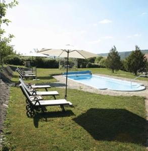 GăneştiBoutique Hotel Le Baron的一组长椅,在游泳池旁边配有遮阳伞