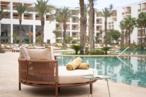 阿加迪尔The View Agadir的藤椅,带枕头和一张桌子,毗邻游泳池