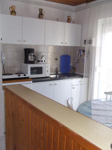 科马罗姆Czanek Apartman的厨房配有白色橱柜和微波炉