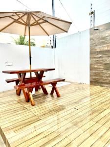 康德Carapibus casa de praia 02的一张带遮阳伞的野餐桌,铺有木地板