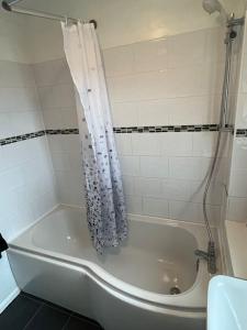 格拉斯哥Spacious home near Glasgow Green的浴室内设有带浴帘的白色浴缸