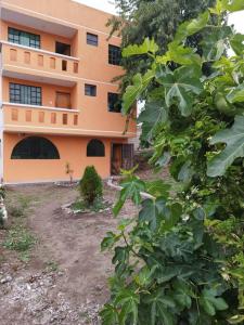安巴托4 Suite Balcón estelar Ambato的一座橙色的建筑,前面有一个院子