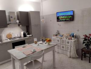 巴尼奥雷焦A CASA IDA的厨房配有白色桌子,墙上配有电视。