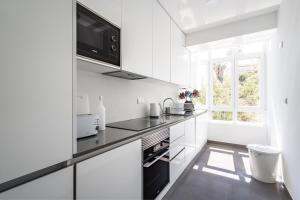 里斯本Akicity Benfica Zenith的白色的厨房配有黑色家电和窗户