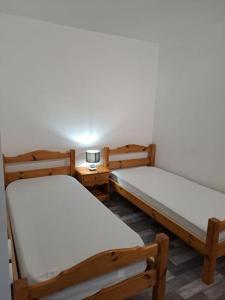 热拉梅Appartement résidence Les Dryades的客房设有两张床和一张带台灯的桌子。