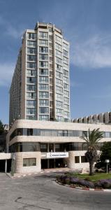 耶路撒冷Shalom Jerusalem Hotel的一座大建筑,前面有棕榈树