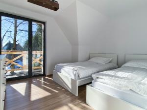 新塔尔格Jankówki - Dom w górach的白色客房的两张床,设有窗户