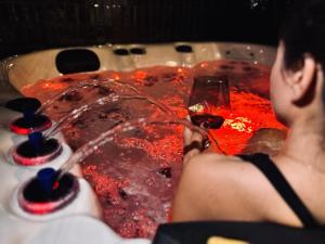 卡托维兹Jacuzzi Loft & Sauna Sanctuary的男人在热水浴缸中拿着一杯葡萄酒