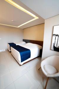 瓜拉普阿瓦Adria Premium Hotel的一间卧室配有两张床和椅子