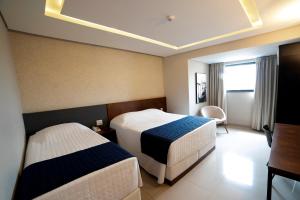 瓜拉普阿瓦Adria Premium Hotel的酒店客房配有两张床和一张书桌