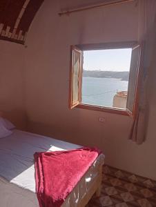 阿斯旺Ramy Heissa Nubian house的一间卧室设有窗户和一张带红色毯子的床