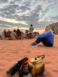 瓦迪拉姆Desert Island Camp的坐在 ⁇ 火旁的女人,带茶壶