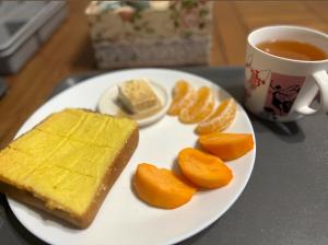 九份九份 珂菲私旅-知雨樓 附心意早餐 Jiufen Cafe Sleep B&B-Rain House 日夜間導覽 合法民宿的一块带面包和橙子的食品和一杯茶