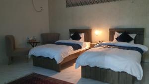 伊斯兰堡Bloom Rooms的一间卧室配有两张床和椅子
