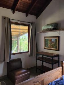 戈亚斯州上帕莱索Refúgio Tao Cerrado Chalé Pé de Serra的一间卧室配有桌子、椅子和窗户
