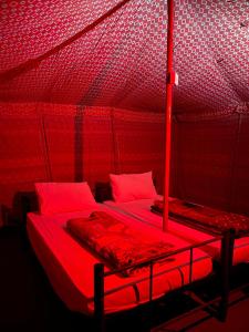 BadīyahSandGlass Camp的红色的房间,帐篷内有两张床