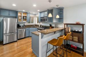 西雅图Aurora Abode BY Betterstay的厨房配有蓝色橱柜和不锈钢用具