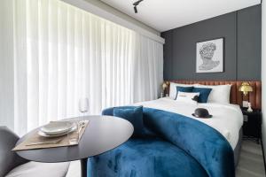 圣保罗Iconyc Charlie Hotel São Paulo - Soft Opening的一间卧室配有一张带蓝色沙发和桌子的床