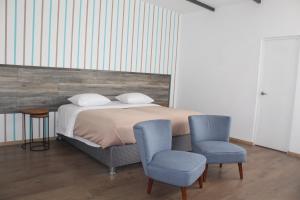塔克纳Basadre Apart Hotel的一间卧室配有一张床和两张蓝色椅子