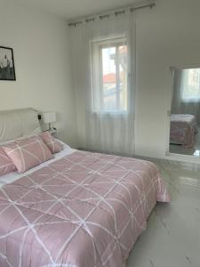 蒂耶内Casa M&N的白色的窗户客房内的粉红色床铺
