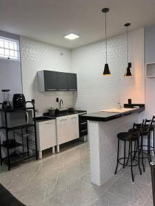 戈亚斯Kitnet Cidade de Goiás - Go #02的厨房配有白色橱柜和黑色台面
