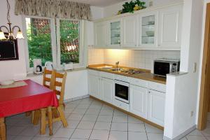 杜亨Padua 4A的厨房配有白色橱柜和一张红色桌子