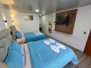 波哥大Hotel Casa Baquero的一间设有两张带蓝色床单和白色鲜花的床的客房