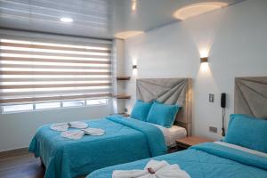波哥大Hotel Casa Baquero的一间卧室设有两张带蓝色床单的床和窗户。