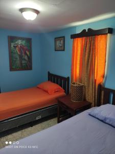 格拉纳达HotelCasaMorazanGranadaNicaragua的蓝色和橙色墙壁的客房内的两张床
