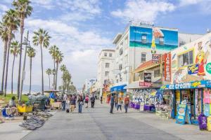 洛杉矶Venice Beach International Traveler Cabins & Suites- Surf & Yoga & E-Bike的一群人沿着一条棕榈树的街道走着