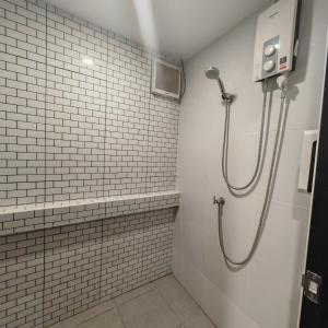 春蓬A lazy person hostel的浴室铺有白色瓷砖,设有淋浴。