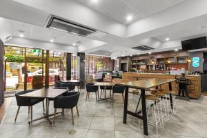 阿德莱德Comfort Hotel Adelaide Meridien的一间带桌椅的餐厅和一间酒吧