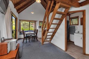 Cable BayMacrocarpa Cottage - Cable Bay Holiday Home的一个小房子里的厨房和用餐室,设有螺旋楼梯