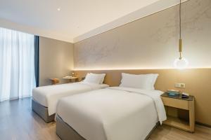 深圳格兰云天·阅酒店(深圳中心公园店)的配有白色床单的酒店客房内的两张床