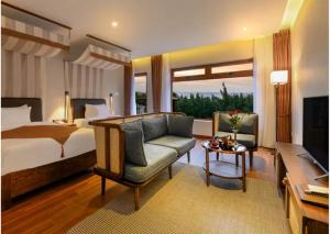 会安Hoi An Ocean Front Hotel的一间卧室配有一张床、一张沙发和一台电视