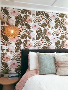 TamahereRustling Oaks NZ Tropical Tiny House的一间卧室设有花卉装饰的墙壁和一张鲜花床。