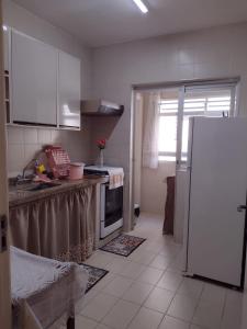 瓜鲁雅Apartamento Na Praia Das Astúrias的厨房配有白色橱柜和冰箱。