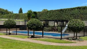 坎布里奇Rustling Oaks NZ Boho Pool House的游泳池前有树木的黑色围栏