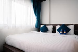 芭东海滩BearPacker Patong Hostel的卧室配有带蓝色枕头的大型白色床