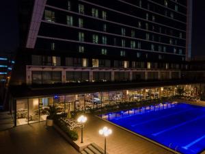 伊斯坦布尔Windsor Hotel & Convention Center Istanbul的夜间在大楼前的游泳池