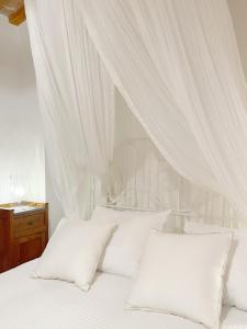 福松布罗内Agriturismo "Le Cannelle" spa & day wellness的白色的床、白色窗帘和枕头