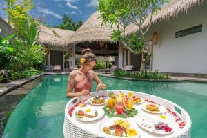 乌布Brand new Luxury 3BR villa Ethnic Ubud #3的一位在游泳池里带餐桌的女人