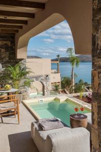 伊罗达Elounda Infinity Exclusive Resort & Spa - Adults Only的户外庭院设有游泳池和桌椅