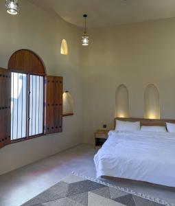 尼兹瓦بيت أرض الثراء Rich Land House的卧室设有一张白色大床和一扇窗户。