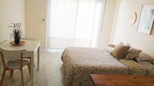 皮内达德马尔Tropical Apartaments Euroviajeros的一间卧室配有一张床、一张桌子和一个窗户。