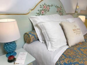利多迪耶索罗Milton Boutique Hotel - Adults Only的一张带白色枕头的床和一张带台灯的桌子