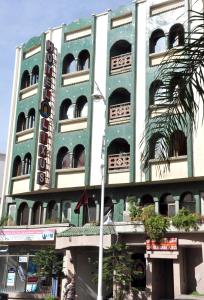 纳祖尔利克苏斯酒店的一座绿色的白色建筑,前面有一棵棕榈树